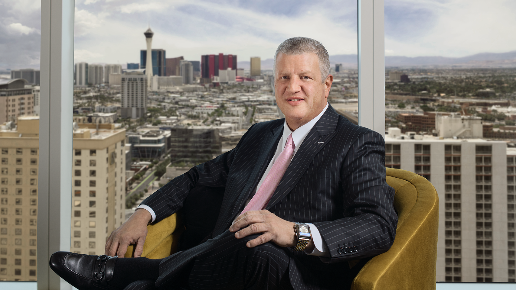 Circa CEO Derek Stevens wearing a black suit sitting in a brown chair with Las Vegas skyline in the background