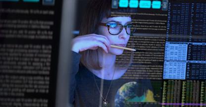 Young woman in glasses looking at code on a monitor