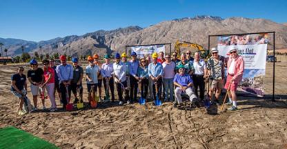 A large group of people posing at a groundbreaking ceremony in the desert