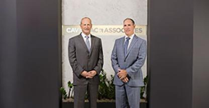 Two businessmen posing in front of the Cavignac & Associates sign