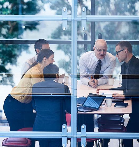 A group of business people gather around a conference room table