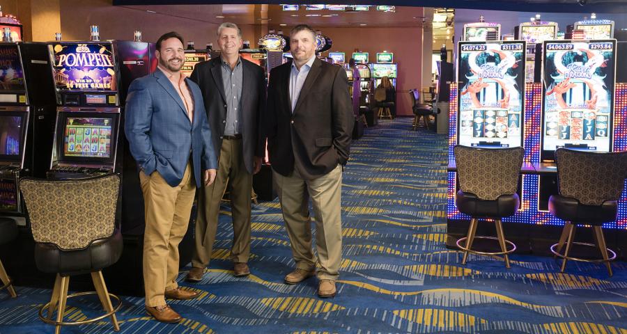 Men in suits standing in a casino, posing for the camera