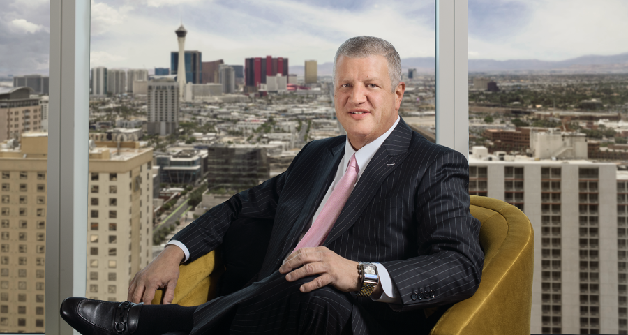 Circa CEO Derek Stevens wearing a black suit sitting in a brown chair with Las Vegas skyline in the background