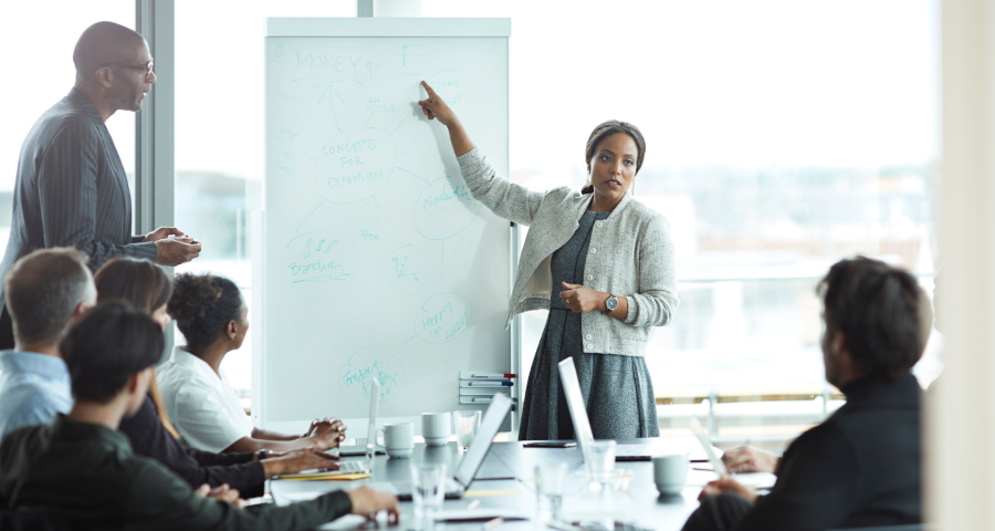 Woman lawyer standing in front of a white board presenting in a meeting.