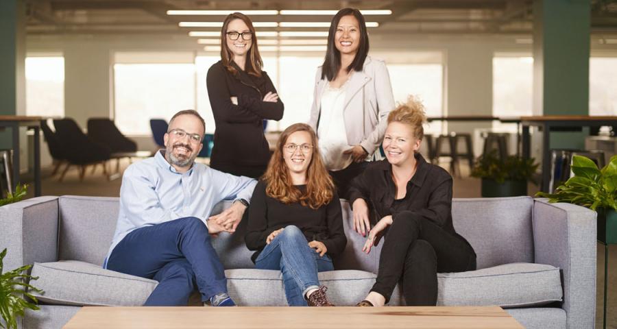 Five professional men and women smiling for a team photo