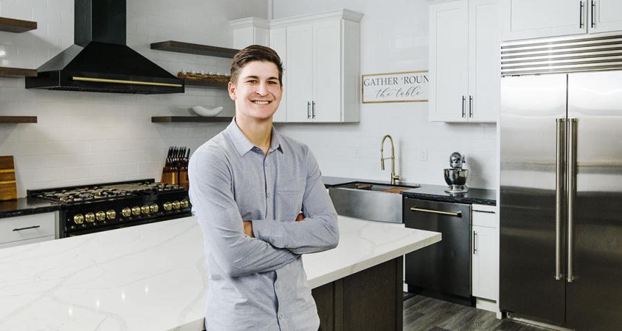 A young man standing in a modern, recently-renovated kitchen