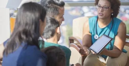 Female doctor showing family results on an iPad while sitting