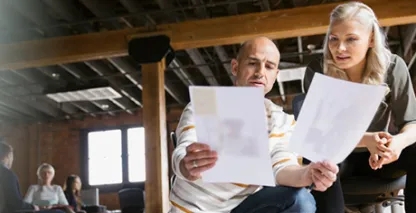 Two people looking at a shared piece of paper.