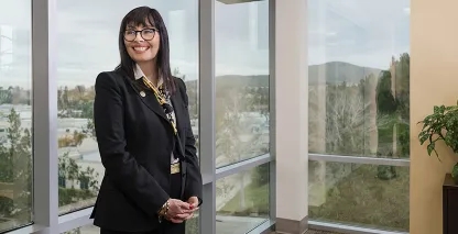 lady left of center in front of windows in office