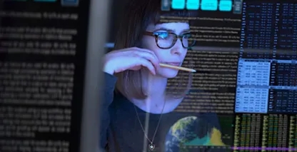 Young woman in glasses looking at code on a monitor