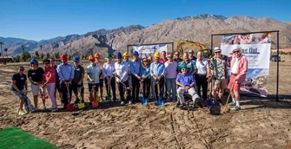 A large group of people posing at a groundbreaking ceremony in the desert