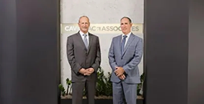 Two businessmen posing in front of the Cavignac & Associates sign