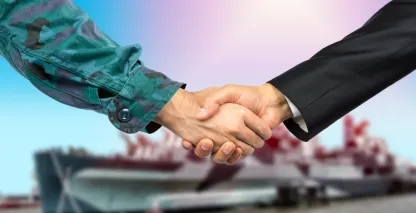 Men shaking hands, one in army camo the other in a business suit
