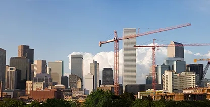 Photo of the Denver skyline with cranes in the foreground. 