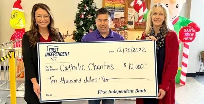 Three representatives from Catholic Charities holding a donation check from First Independent Bank
