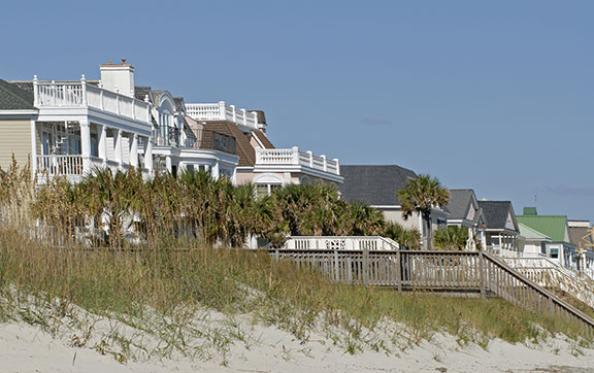 Beach homes viewed from the shore, with peers extending onto the sand
