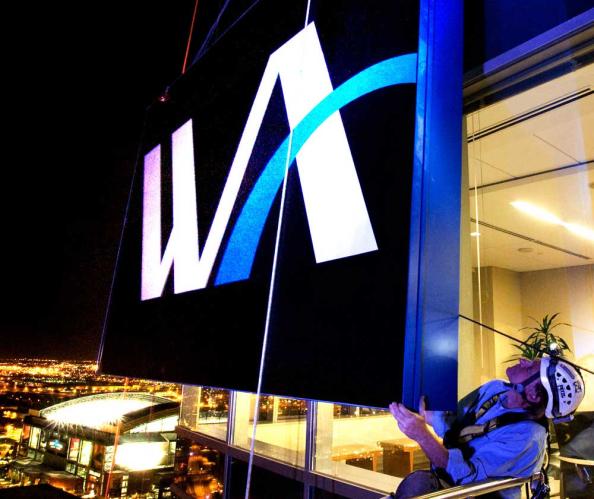 A man atop on a skyscraper scaffold as the Western Alliance sign is going up